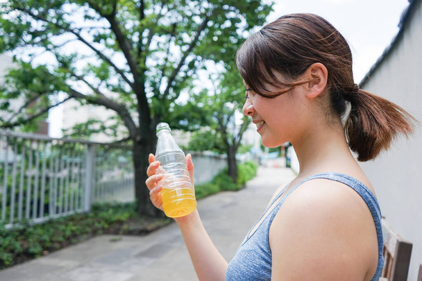 Mujer joven manteniéndose hidratada durante el deporte - Foto, Imagen