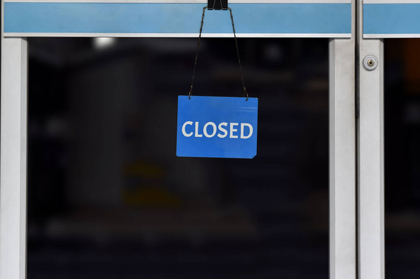 Egy tábla "zárt" lóg az üvegajtón egy boltban, Közel pénzügyi nehézségek és gazdasági válság miatt. - Fotó, kép
