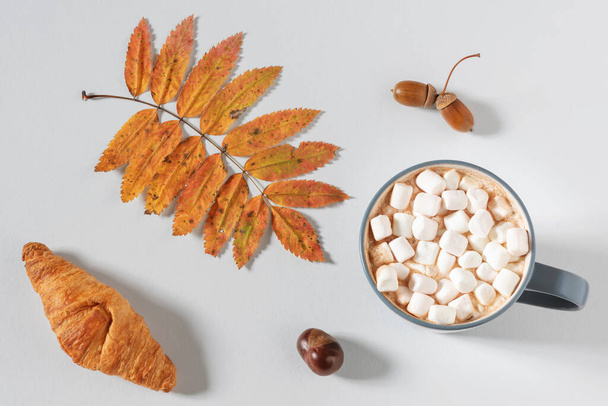 Cup of hot chocolate and croissant with autumn leaf - Photo, Image