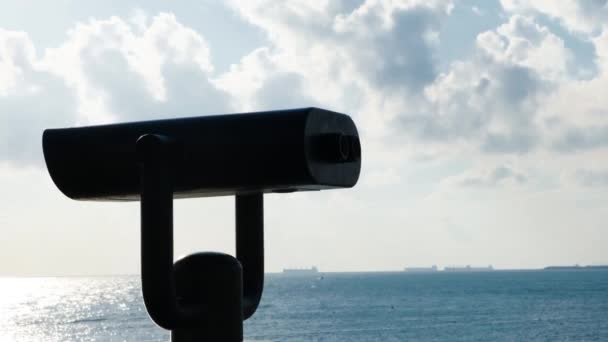 Binokuláry na pozorovací palubě na pozadí moře. Koncept. Černý moderní dalekohled pro pozorování teritoria na pobřeží. Turistická zábava v podobě dalekohledu po moři za slunečného dne - Záběry, video
