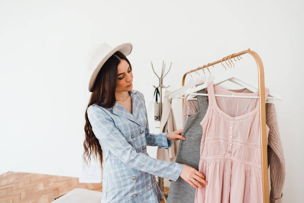 Stylish caucasian young woman in hat and business suit in fashion boutique while shopping. High quality photo - Foto, imagen