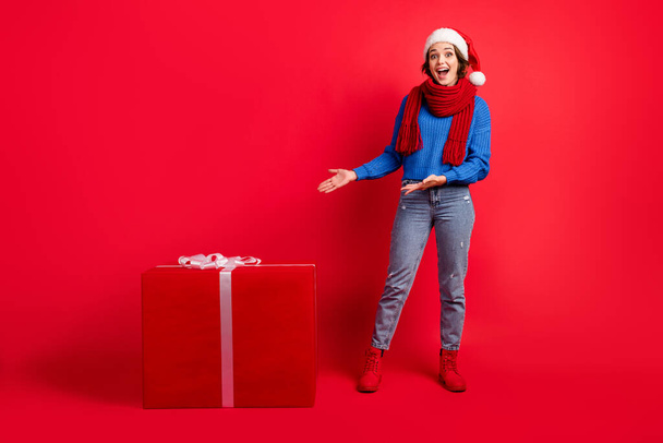 Full length body size view of her she attractive amazed cheerful cheery glad girl presenting demonstrating large big gift shop order delivery isolated bright vivid shine vibrant red color background - Foto, immagini