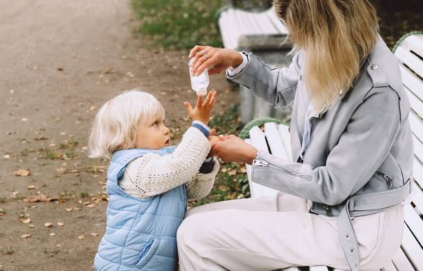Mother applies sanitizer on her little sons hands. - Foto, Imagen