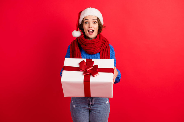 Photo astonished girl in santa claus headwear get receive gift box christmas midnight party scream wow omg wear knitted pullover denim jeans isolated bright shine color background - Foto, immagini