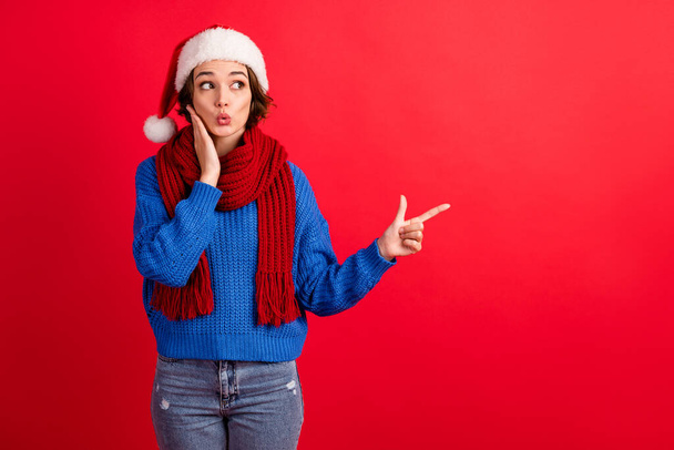 Shocked girl in santa claus headwear impressed christmas season shopping discount point finger copyspace touch hands face wear blue knitted pullover isolated bright shine color background - Photo, Image