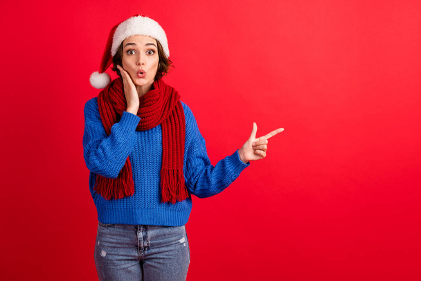 Photo astonished girl in santa claus headwear impressed season shopping miracle sale point finger copyspace wear blue knitted sweater denim isolated bright shine color background - Φωτογραφία, εικόνα