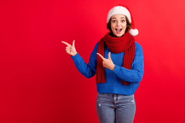 Surprised shocked girl in santa claus headwear cap point finger copyspace impressed season tradition discount wear blue knitted pullover denim jeans isolated bright shine color background - Foto, imagen