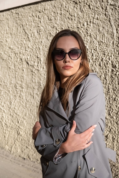 atraente jovem asiático modelo no cinza trincheira casaco de pé perto da parede ao ar livre - Foto, Imagem