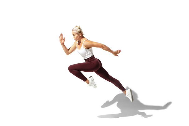 Beautiful young female athlete practicing on white studio background with shadow - Foto, immagini