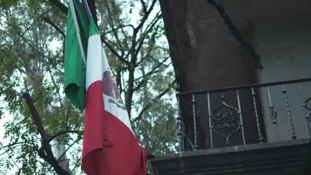 4k Μεξικανική σημαία Δίπλα σε ένα μεταλλικό μπαλκόνι και ένα δέντρο - Πλάνα, βίντεο