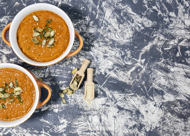 pumpkin cream soup with seeds, sesame and rucola on a grey background. Autumn flat lay. Top view. Cozy photo. - Photo, Image