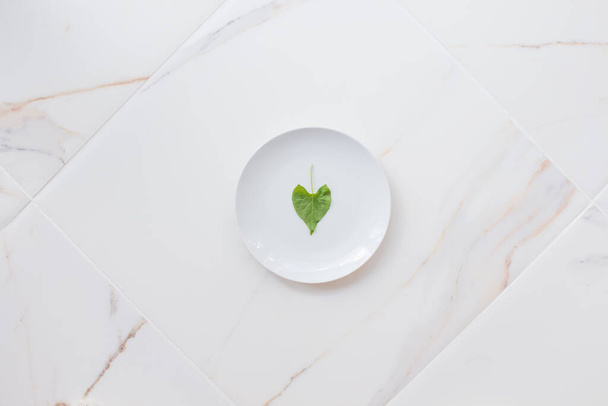 Концепция диеты и похудения, пост и очищение организма. Пустая белая тарелка на белом мраморном столе. Очистите организм зелеными продуктами - Фото, изображение