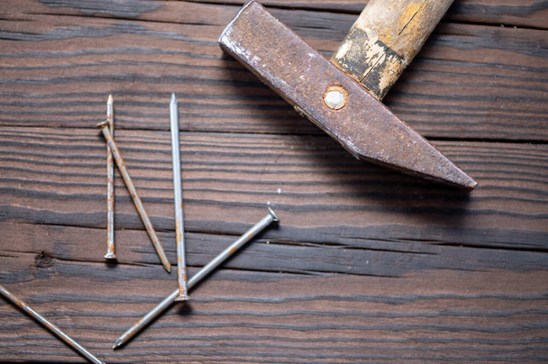 Old vintage hammer and nails on a wooden background, close-up, selective focus - Фото, зображення
