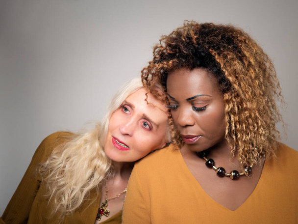 Horizontal portrait of a white woman resting her head on her black female friend's shoulder - Photo, Image
