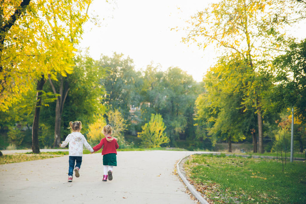 dos niñas novias jugando en el parque de otoño de la ciudad de la mano actividades - Foto, Imagen