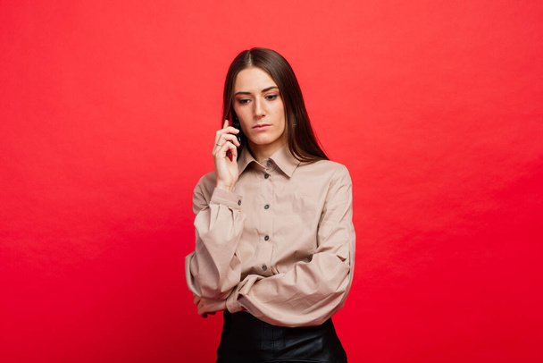 Surprised young woman using smart phone, red background - Foto, Imagem