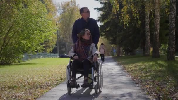 Sonbahar parkında sevgilisiyle tekerlekli sandalyede olan bir kadın. - Video, Çekim
