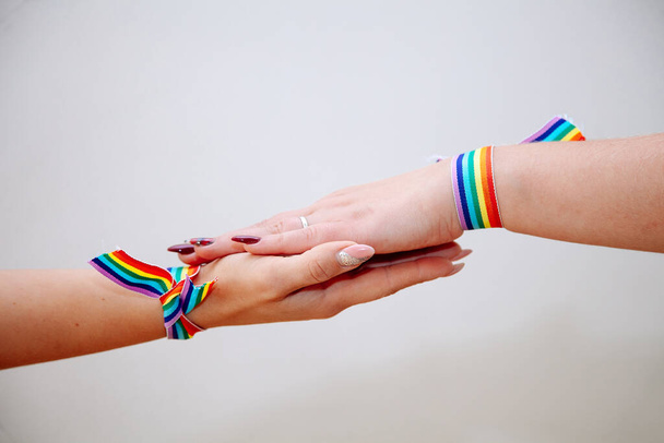 Ein weibliches Handzeichen mit Armband in Regenbogenfarben auf weißem Hintergrund, Feier des Gay Pride, Das Symbol der schwulen, lesbischen, bisexuellen und transsexuellen, LGBT sozialen Bewegungen. - Foto, Bild