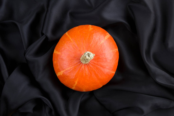 Top view of pumpkin in the center of the black silk background closeup - Zdjęcie, obraz