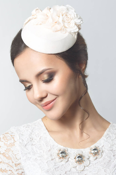 Beauty portrait of an elegant brunette bride in a small hat isolated on a gray background. - Фото, изображение