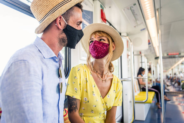 Mooi koppel rijdend op een metro wagon tijdens covid-19 pandemie, concepten over levensstijl, trasportatie en sociale afstand - Foto, afbeelding