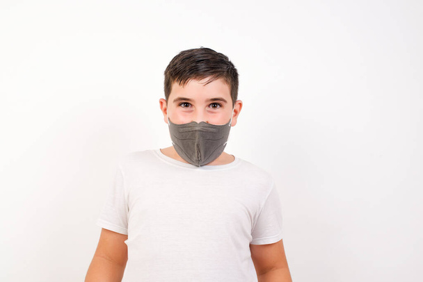 Close up portrait of handsome caucasian boy wearing medical mask isolated on white background big eyes and wide open mouth. - Foto, afbeelding