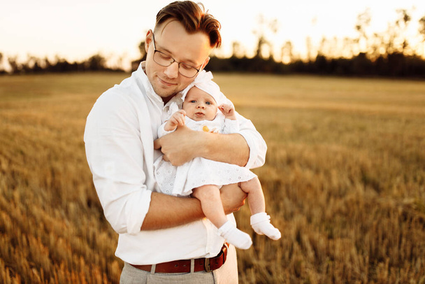 Handsome father with adorable little daughter at the field, caring dad hold cute newborn baby girl in arms, tender family moments, parenting and fatherhood concept  - Fotoğraf, Görsel