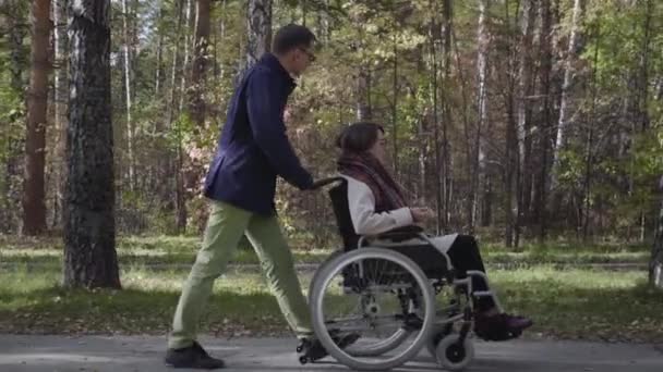 Tekerlekli sandalyede erkek arkadaşıyla yürüyen kadın. - Video, Çekim