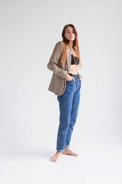 young caucasian woman in black top, blue jeans and suit jacket isolated on white - Foto, afbeelding