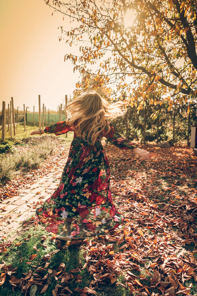child in beautiful dress dancing wild in sunny afternoon - Foto, afbeelding