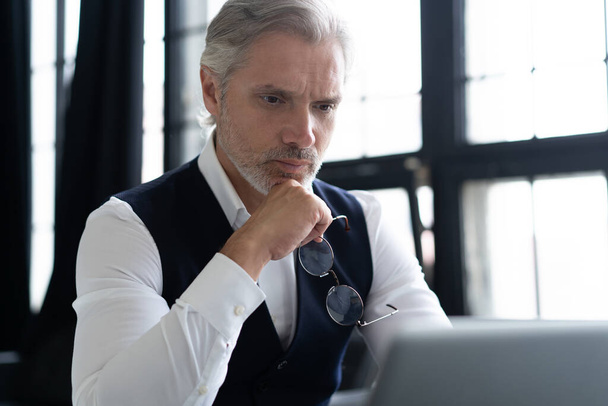 Concentrated at work. Mature man in full suit using laptop while working in modern office. - Foto, imagen