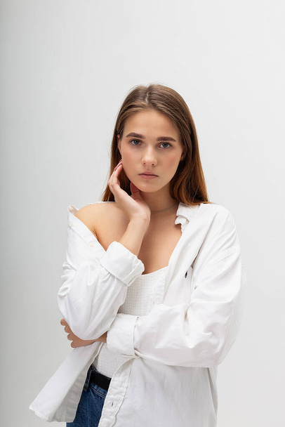 young caucasian woman with long hair in shirt and blue jeans on white background - Fotó, kép