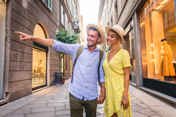 Beautiful couple of lovers shopping in the city centre - Playful tourists visiting a famous european city - Photo, image