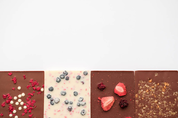 Handmade milk and white chocolate bars with a variety of dried fruit toppings. Top view. - Photo, image