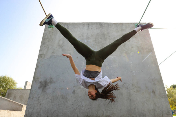 Tyttö hyppää ylösalaisin betoniseinää vasten - Valokuva, kuva