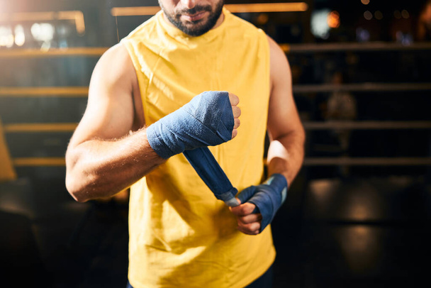 Athletic man wrapping his arm into boxing wraps - Foto, Imagem