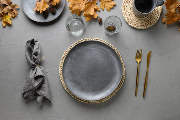 Autumn festive table setting with fall golden decor and empty plate for design on grey table. Flat lay, top view. - Foto, Imagen