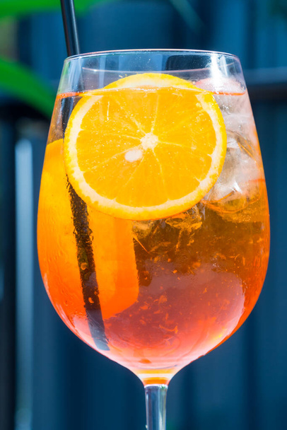 Egy pohár alkoholos Aperol Spritz koktélt jégkockákkal és narancsszeletekkel. Klasszikus olasz trendi koktélital. Sötét háttér, szelektív fókusz - Fotó, kép