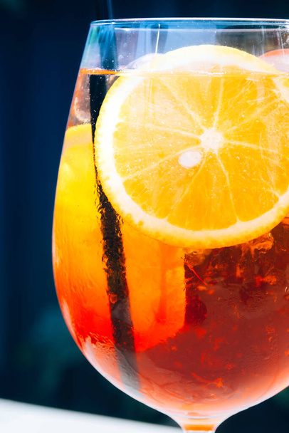 Glas alkoholischer Aperol Spritz Cocktail mit Eiswürfeln und Orangenscheiben. Klassischer italienischer trendiger Cocktaildrink. Dunkler Hintergrund, selektiver Fokus - Foto, Bild