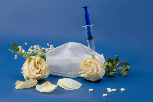 The concept of death from infectious diseases. Mask, dried flowers and syringe - Φωτογραφία, εικόνα