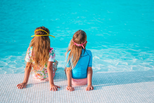 Αξιολάτρευτα μικρά κορίτσια που παίζουν σε εξωτερική πισίνα στις διακοπές - Φωτογραφία, εικόνα