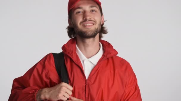 Привабливий хлопець доставки в червоній шапці і куртці щасливо махає так і показує великий палець вгору жест ізольовано. Добре зроблений вираз
 - Кадри, відео