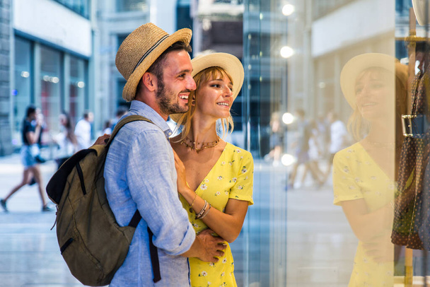 Beautiful couple of lovers shopping in the city centre - Playful tourists visiting a famous european city - Fotó, kép