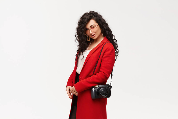 Fashionable elegant woman posing in red coat and round sunglasses, isolated on white. - 写真・画像