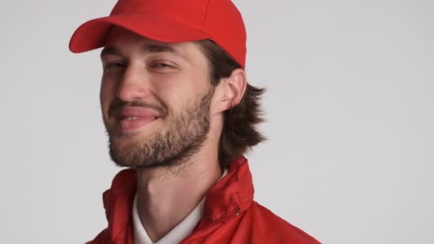 Gros plan joyeux livreur gars en chapeau rouge regardant joyeusement dans la caméra et agitant oui sur fond blanc - Séquence, vidéo
