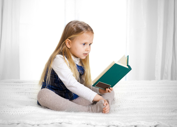 Scared cute blonde haired school girl reading a book - 写真・画像