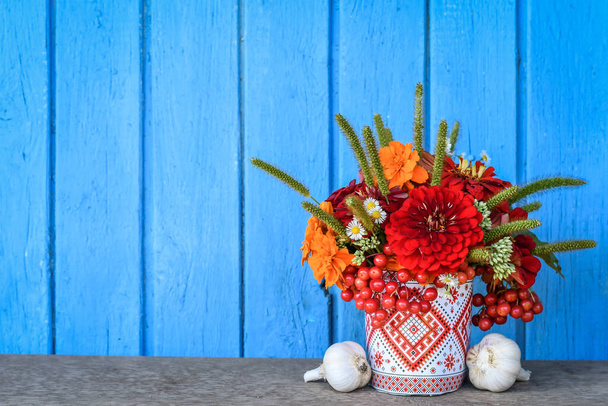 Bodegón con flores rojas y amarillas sobre fondo rústico de madera azul. Copiar espacio. - Foto, imagen