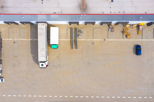 Luftaufnahme eines Warenlagers. Logistikzentrum im Industriegebiet von oben. Luftaufnahme der LKW-Beladung im Logistikzentrum. Blick von der Drohne. - Foto, Bild
