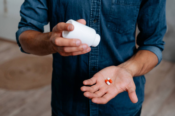 young man holds pills in the palm of his hand. - 写真・画像