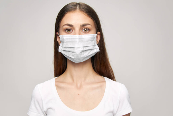 egy lány orvosi maszkkal az arcán és fehér pólóban.  - Fotó, kép